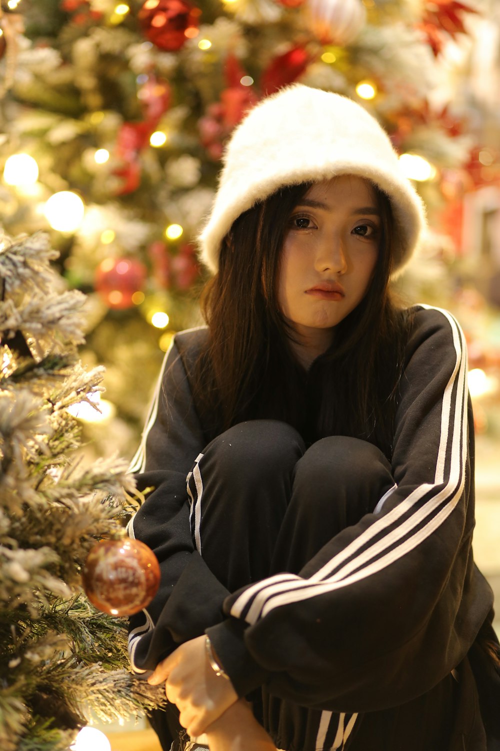 a young girl sitting in front of a christmas tree