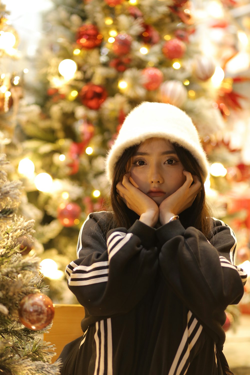a young girl sitting in front of a christmas tree