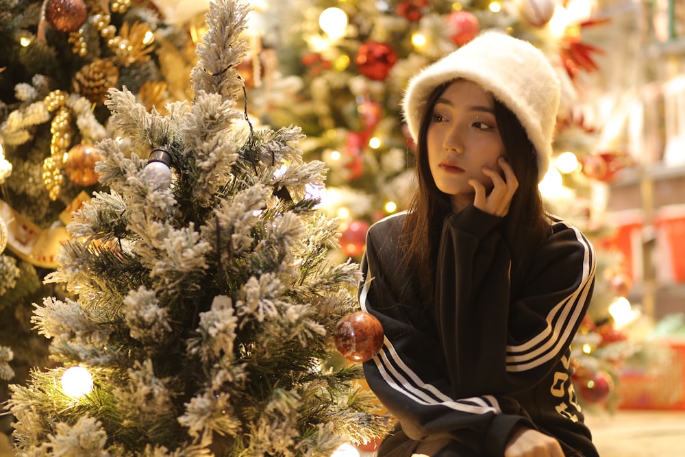 a woman sitting on a bench in front of a christmas tree