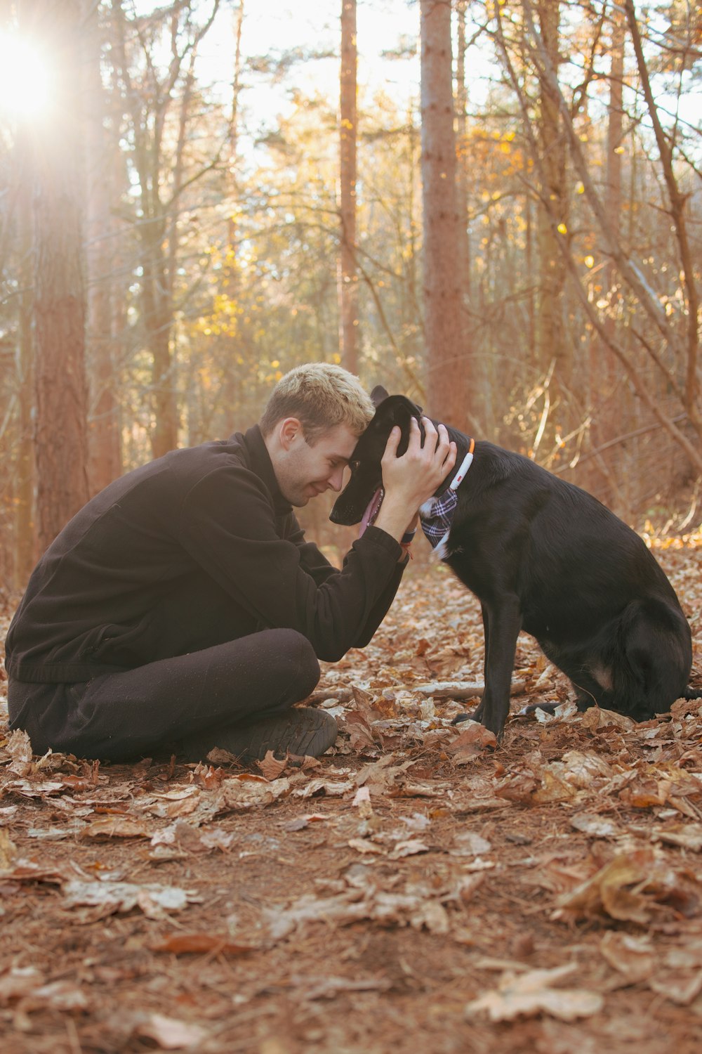 a man kneeling down next to a black dog