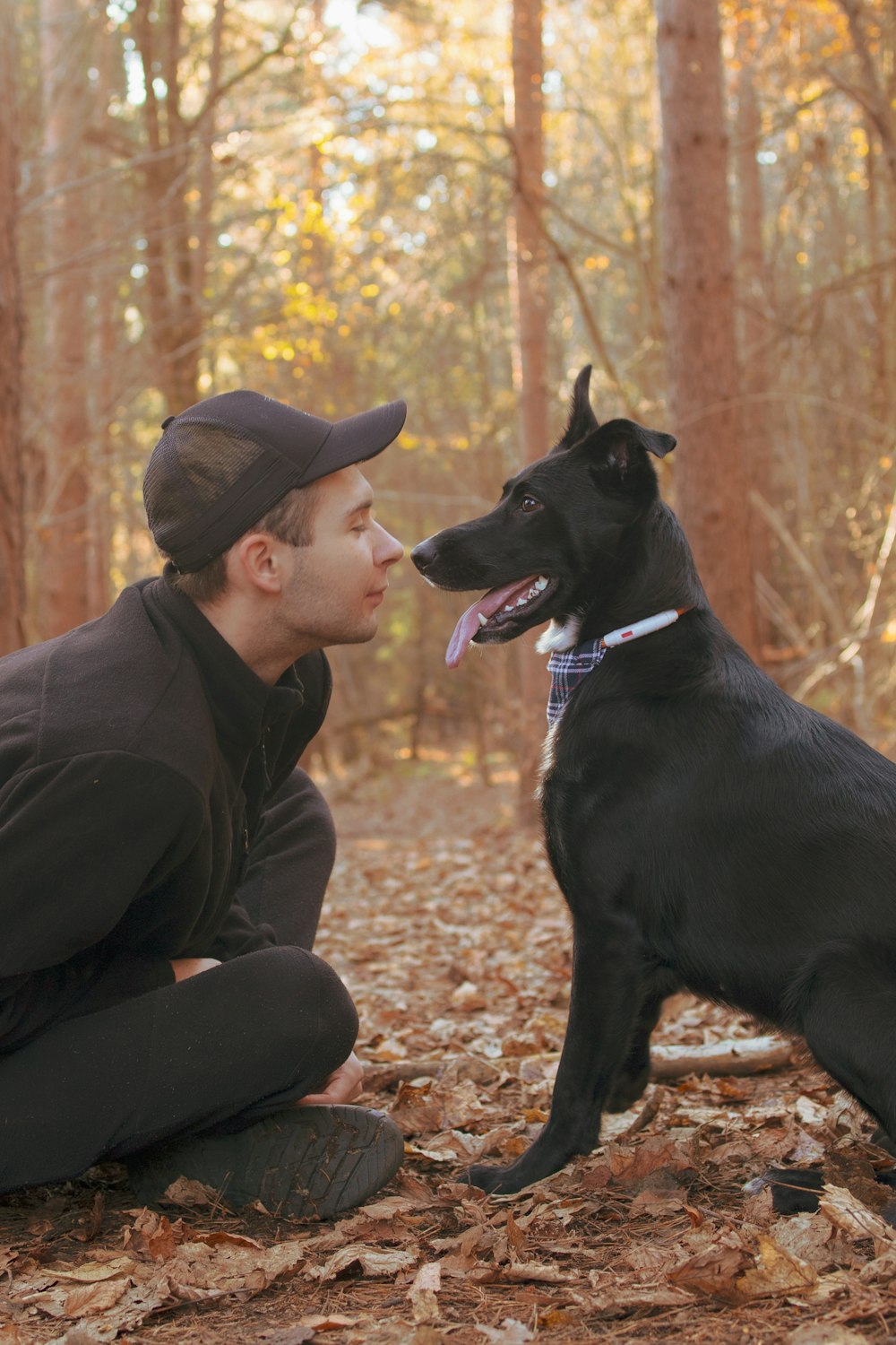 Un hombre arrodillado junto a un perro negro