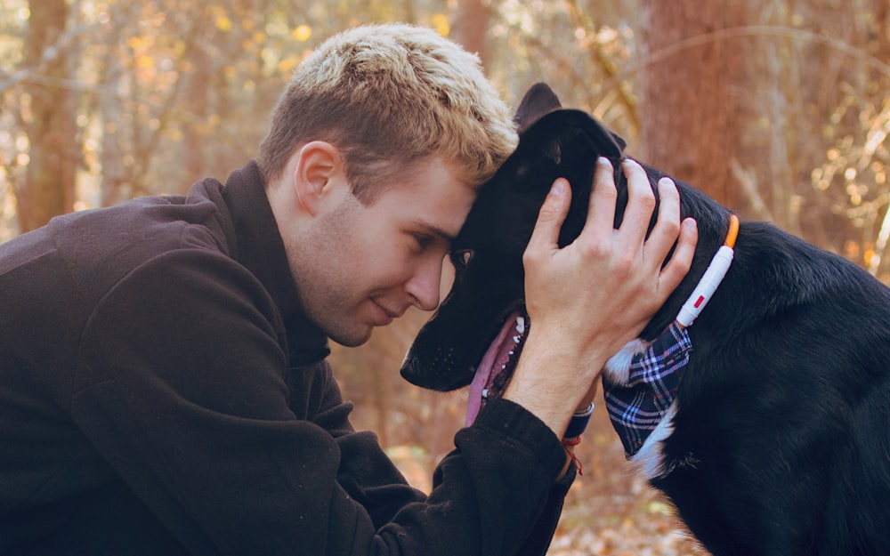 a man is petting a dog in the woods