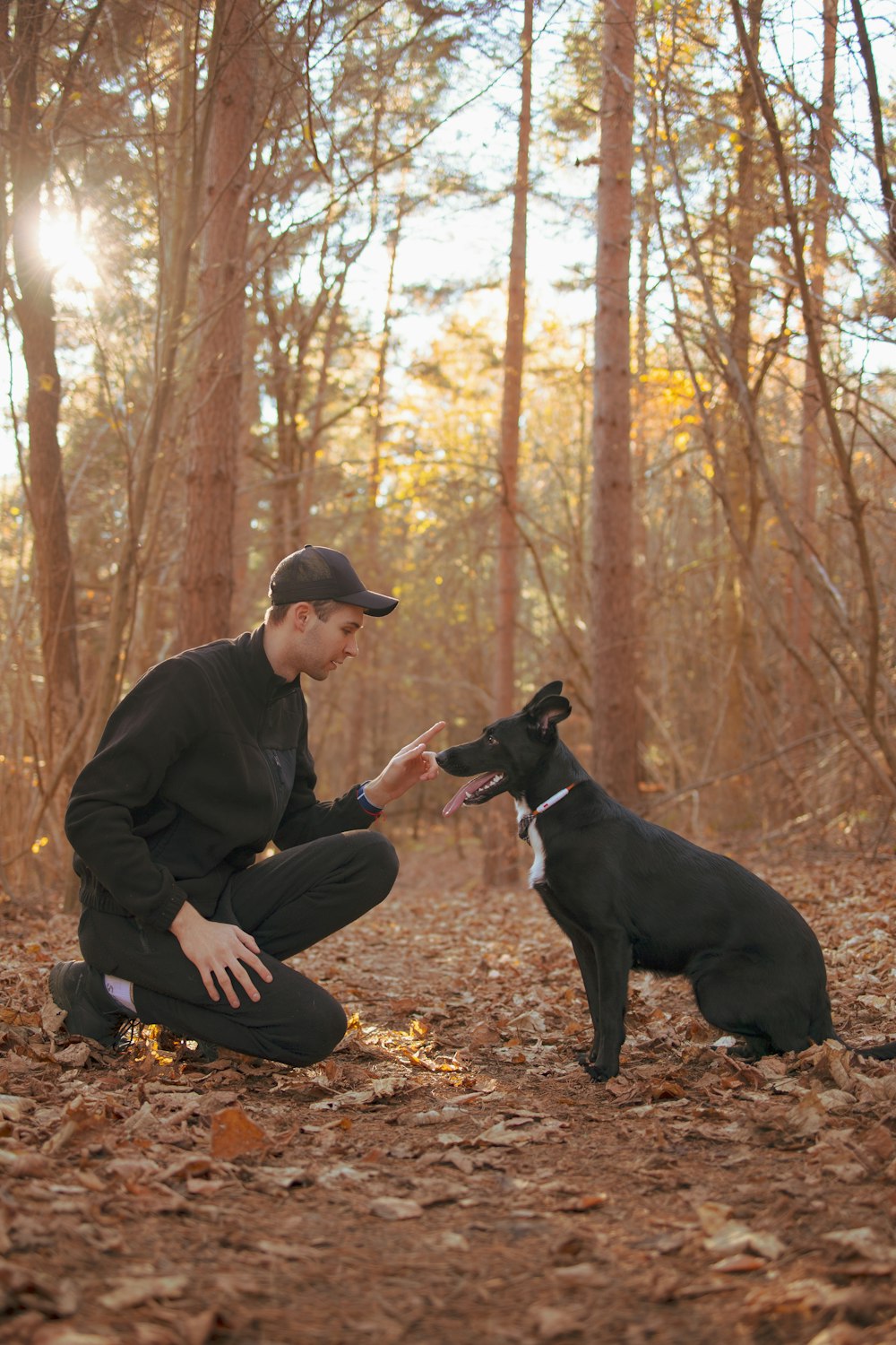 a man kneeling down next to a black dog