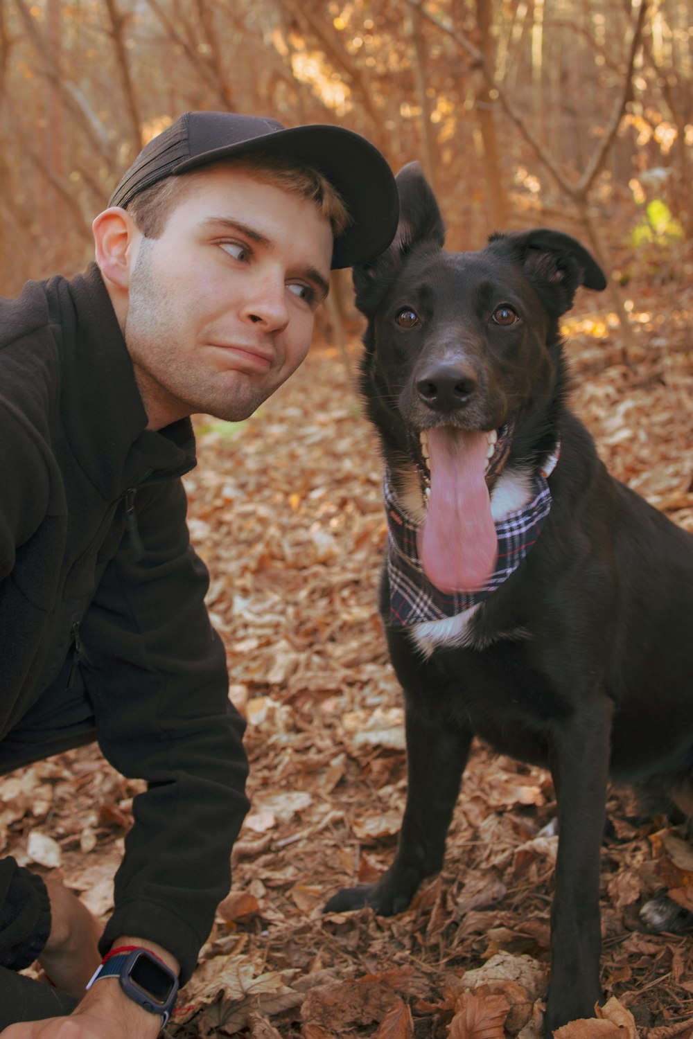 Un hombre arrodillado junto a un perro negro