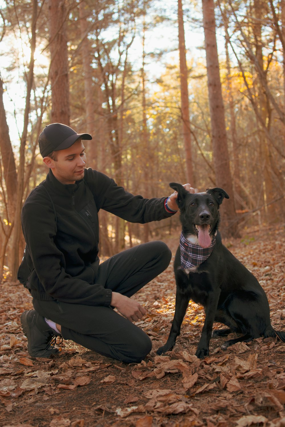 a man kneeling down next to a black dog