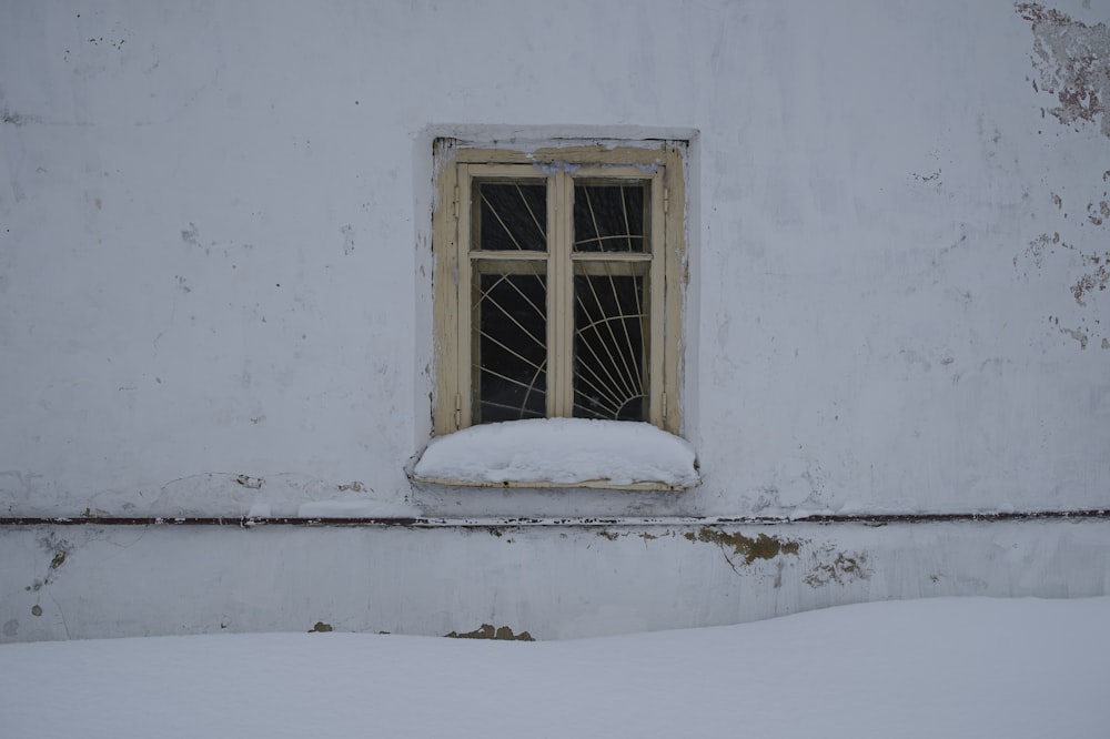 a window in a white building with snow on the ground