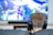 A person with short brown hair is sitting on a couch wearing black headphones. In front of them is a large screen displaying a video game with vibrant colors and dynamic visuals. The focus is on the person from behind, emphasizing the immersive gaming experience.