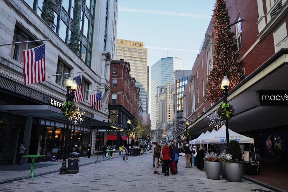 a group of people walking down a street next to tall buildings