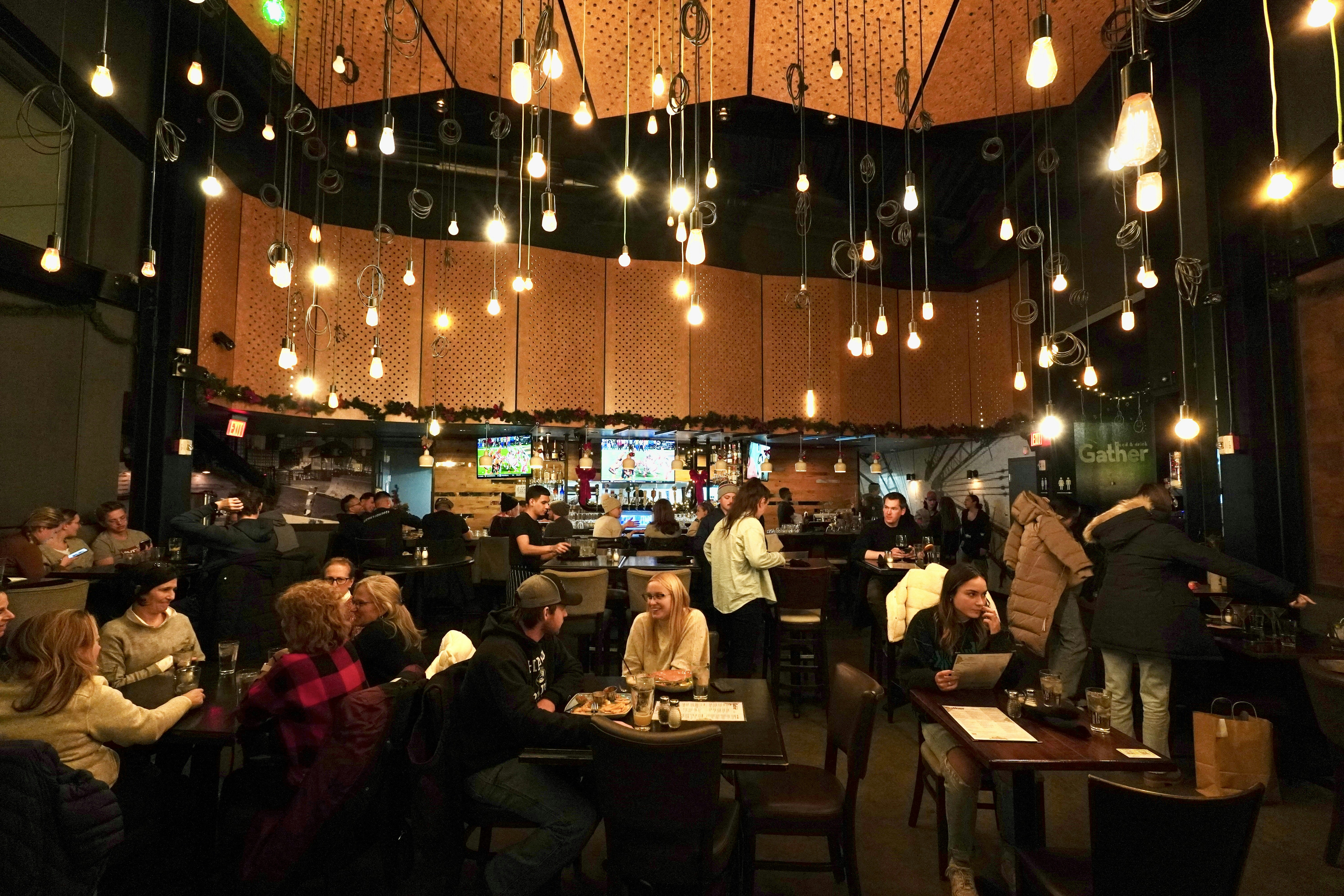 a group of people sitting at tables in a restaurant, 