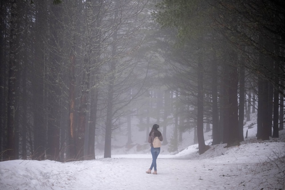 a woman is walking through the snow in the woods