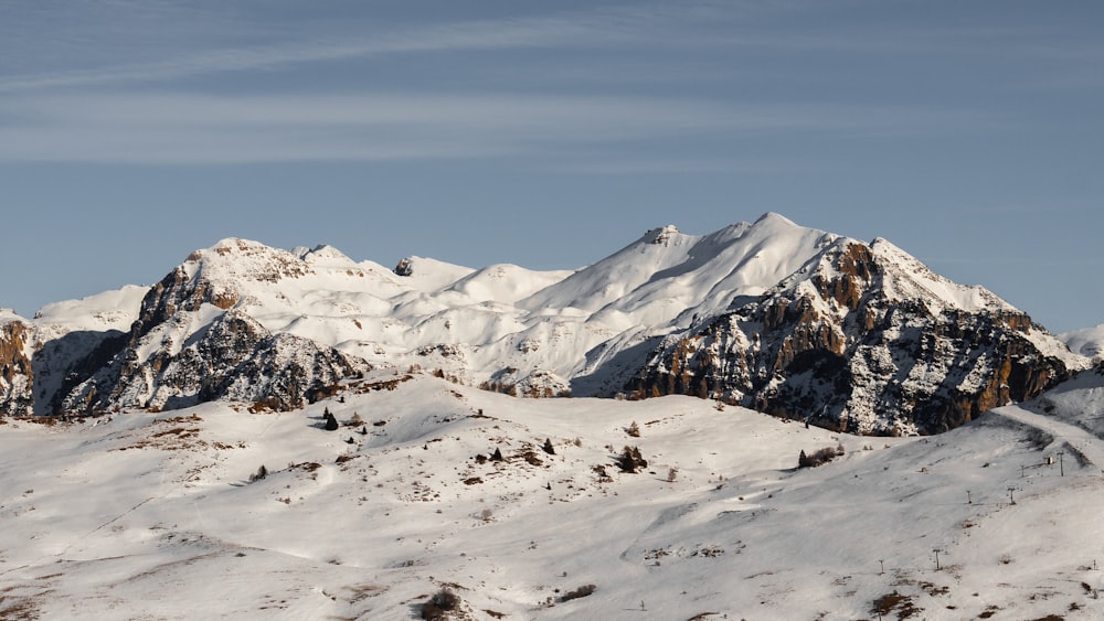 a mountain range covered in snow under a blue sky