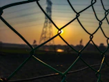 Wide shot of a newly secured perimeter fence surrounding a property at sunset.