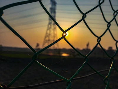 Wide shot of a newly secured perimeter fence surrounding a property at sunset.