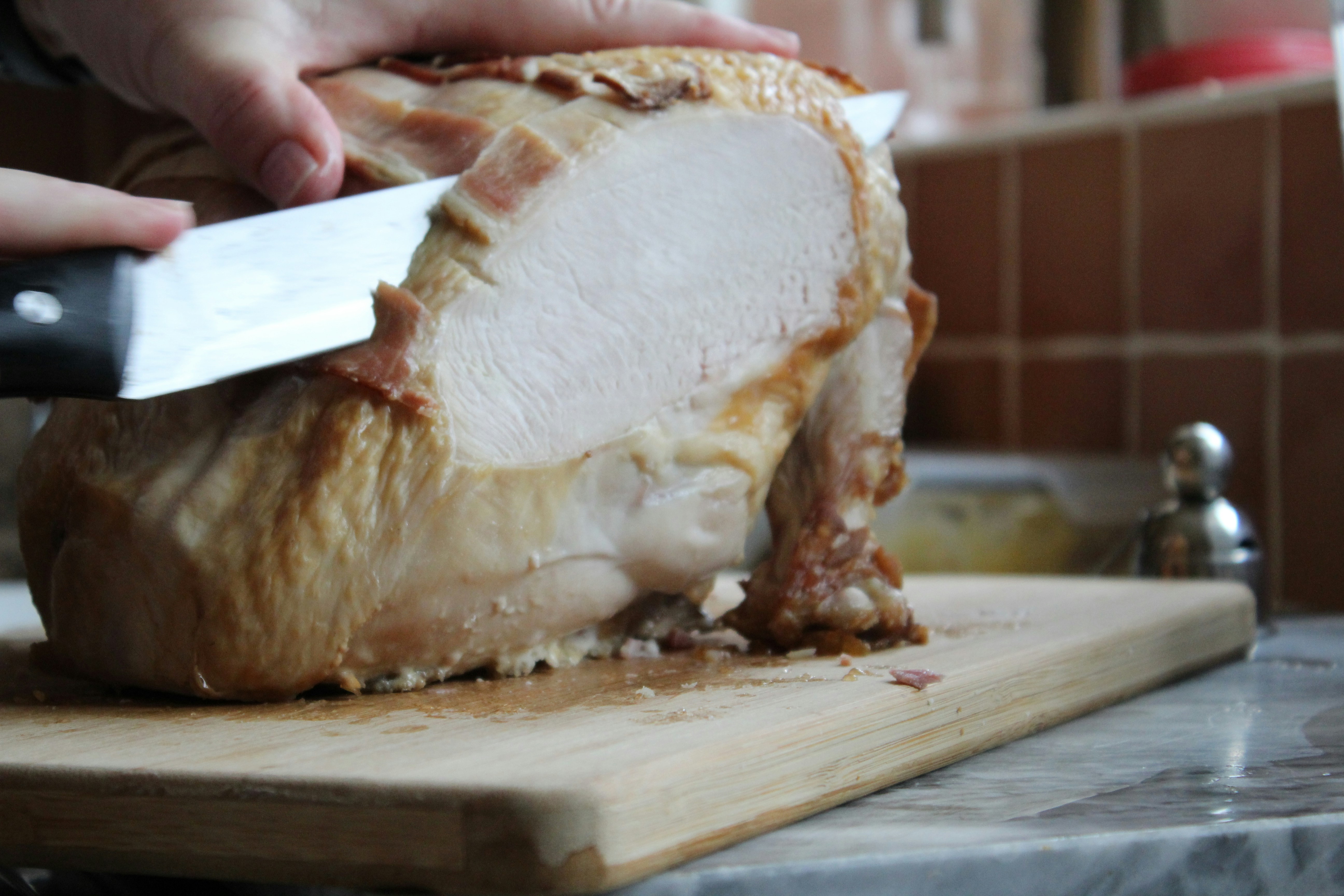 a person slicing a turkey on a cutting board, 