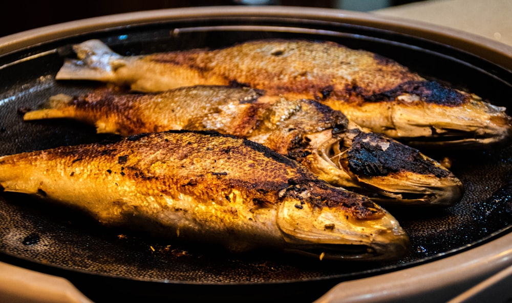 a frying pan filled with fish on top of a stove