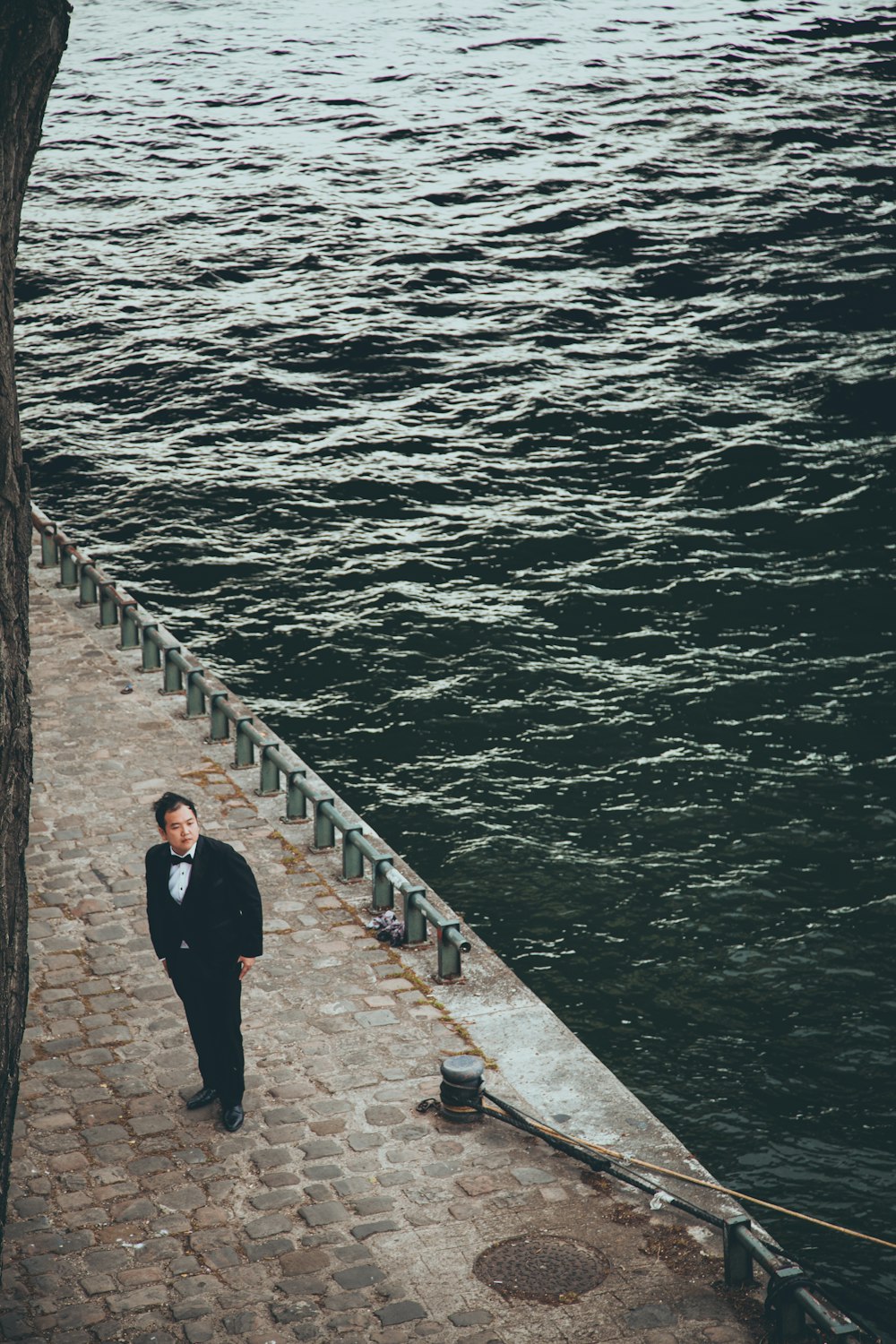 a man in a tuxedo walking down a stone walkway