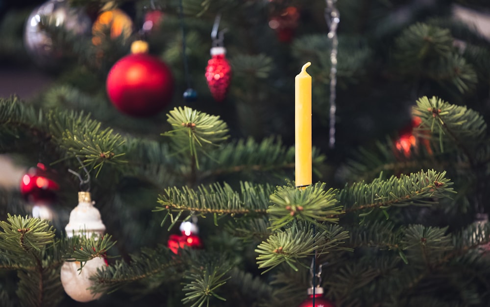 Una vela encendida en un árbol de Navidad rodeada de adornos