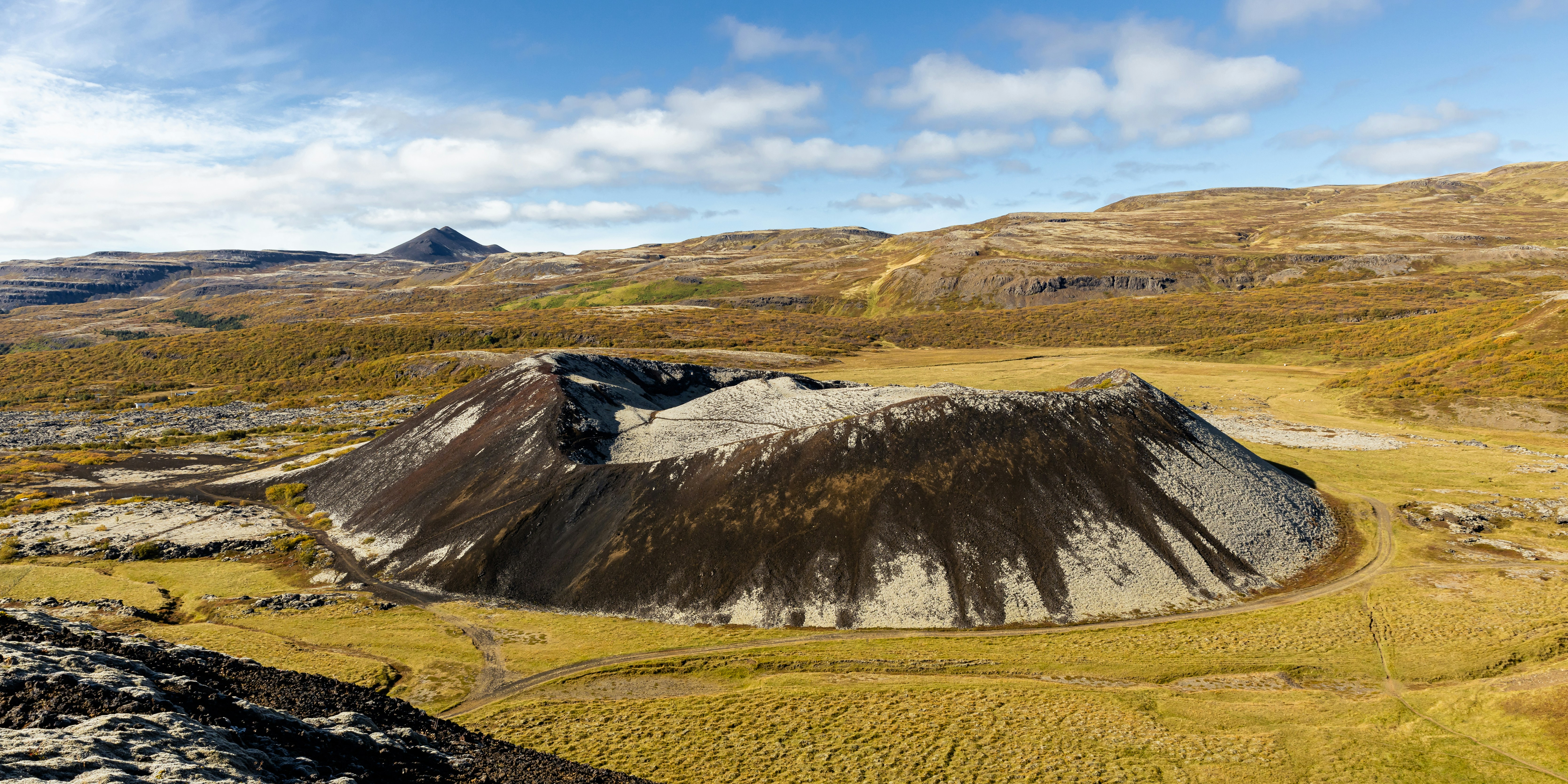 a large hill with a grassy field below it