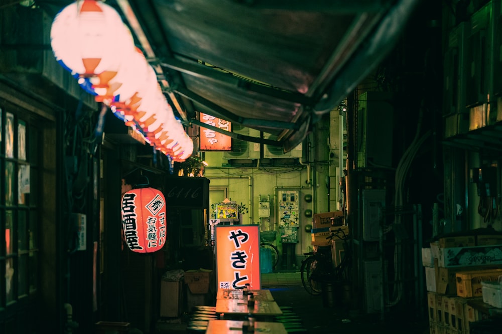 a narrow alley way with signs and lanterns hanging from the ceiling