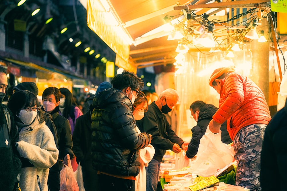 a group of people standing around a table filled with food