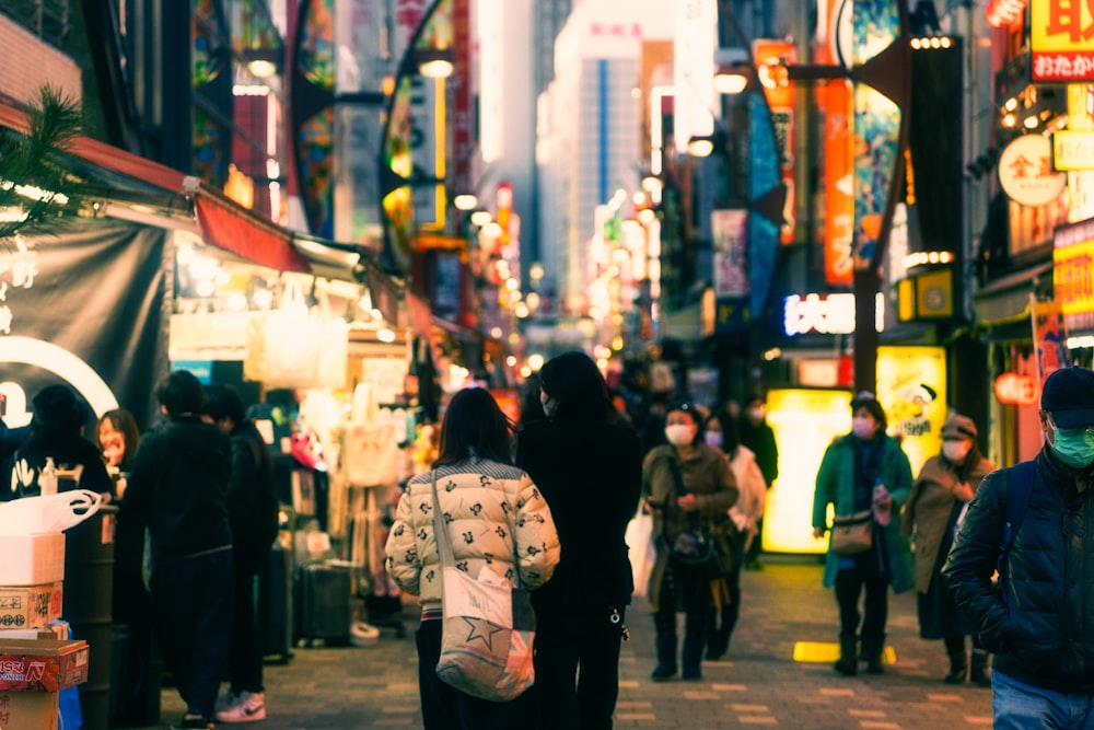 a group of people walking down a street next to tall buildings