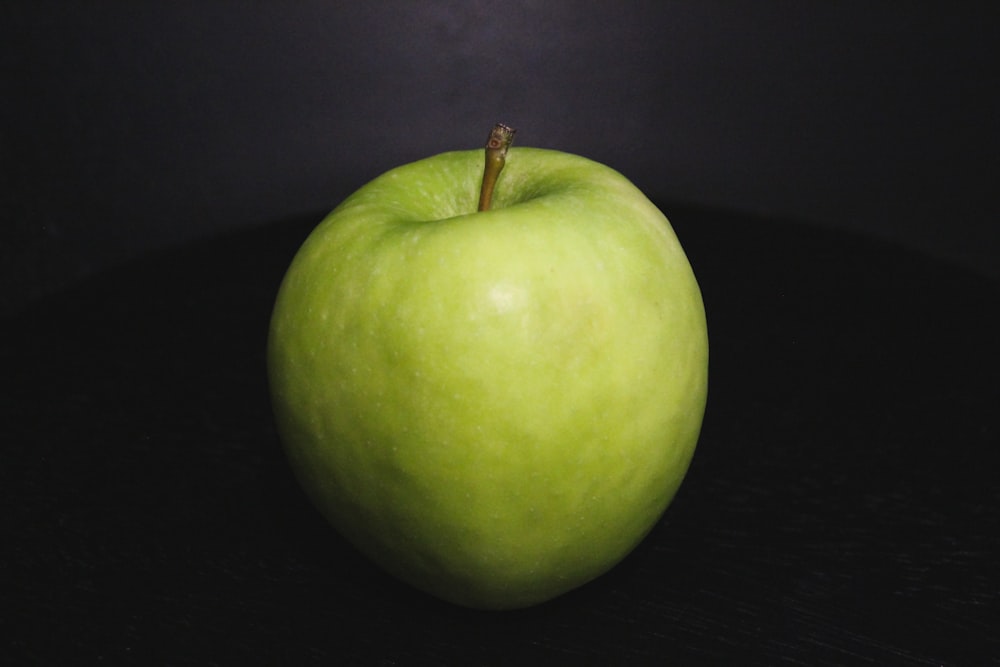 una mela verde seduta sopra un tavolo