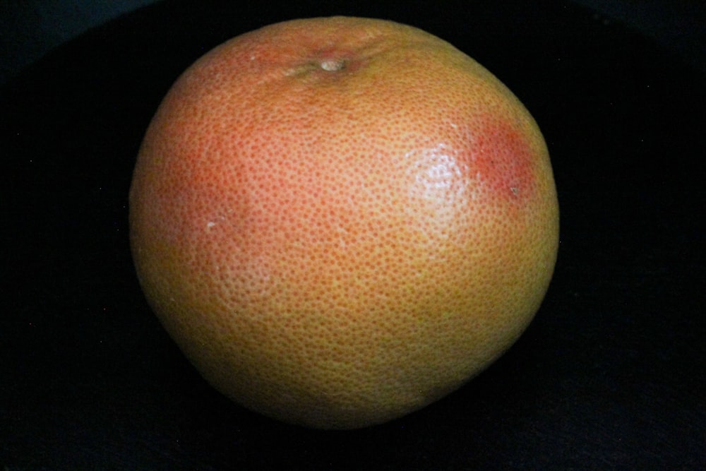 a close up of an orange on a black surface