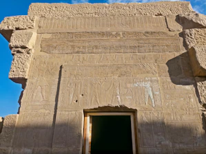 A close-up of weathered Egyptian megaliths bathed in warm sunlight, revealing intricate carvings and ancient symbols.