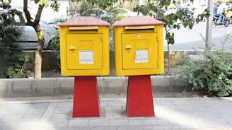 two yellow and red mail boxes sitting on top of a sidewalk