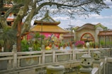 Traditional Asian temple surrounded by lush greenery and blooming flowers.