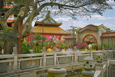 Traditional Asian temple surrounded by lush greenery and blooming flowers.