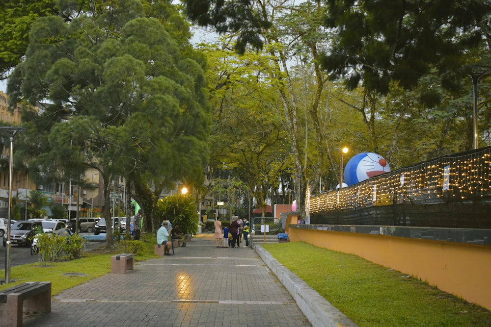 people walking down a sidewalk next to a park