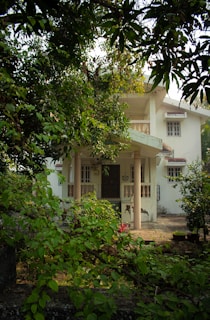 a white house surrounded by trees and bushes