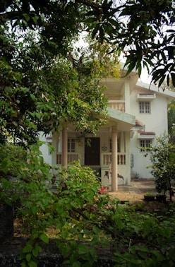 a white house surrounded by trees and bushes