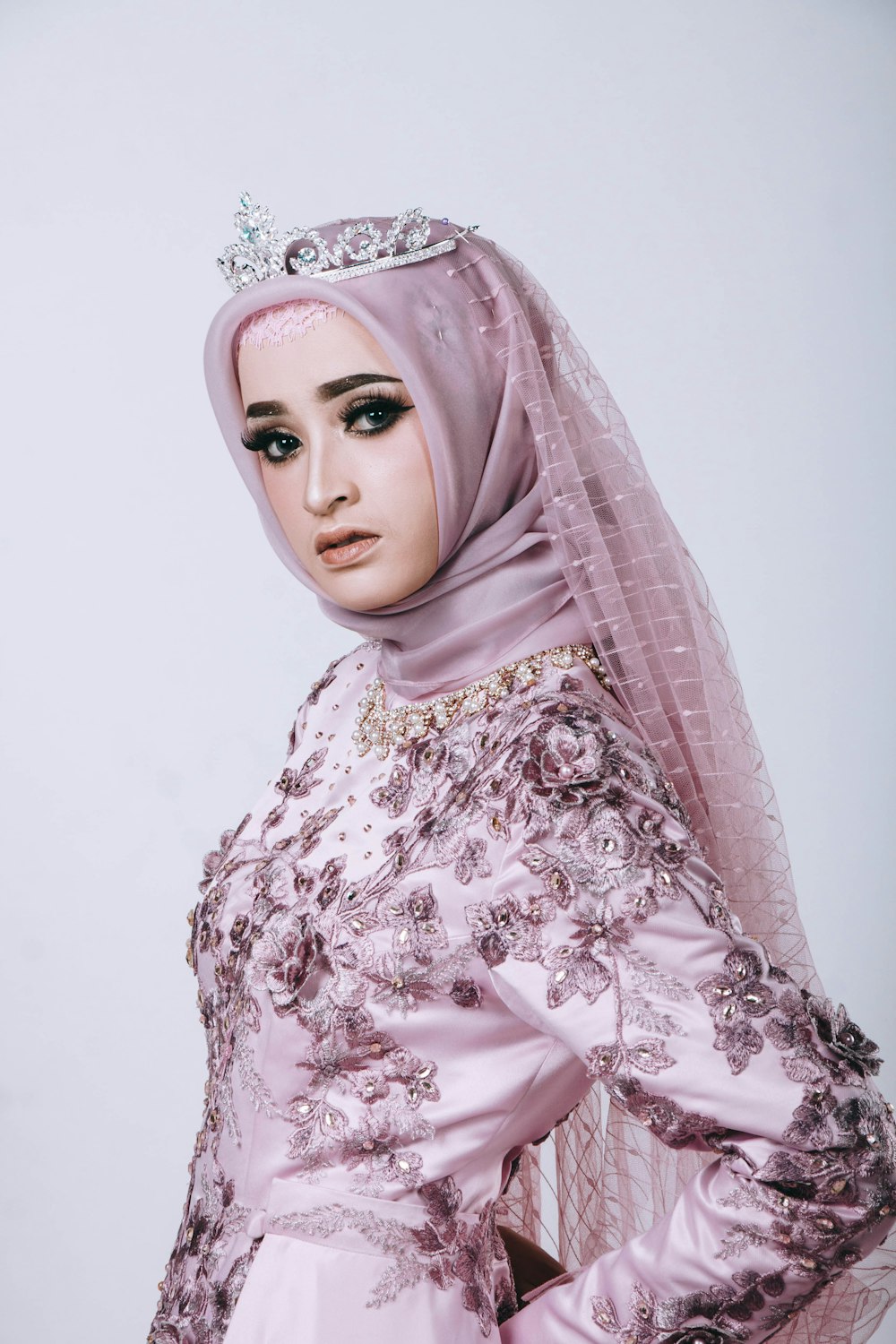 a woman in a pink hijab wearing a tiara