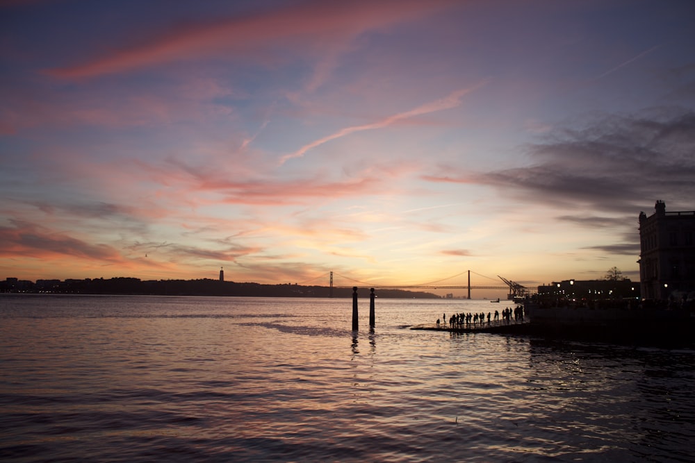 a sunset over a body of water with a bridge in the background