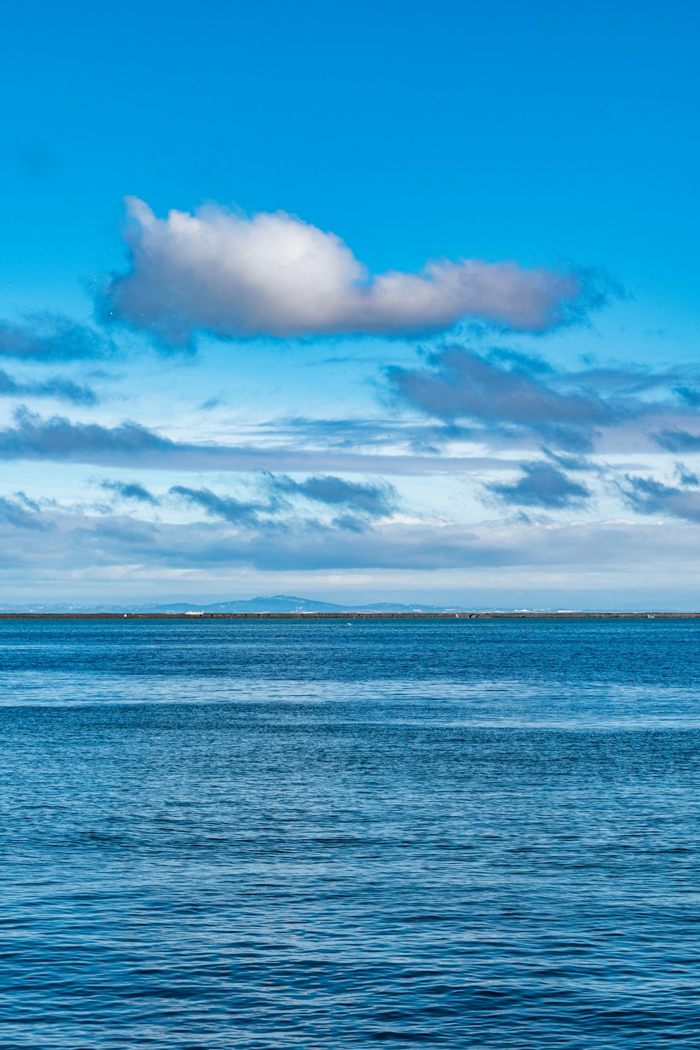 a large body of water sitting under a cloudy blue sky