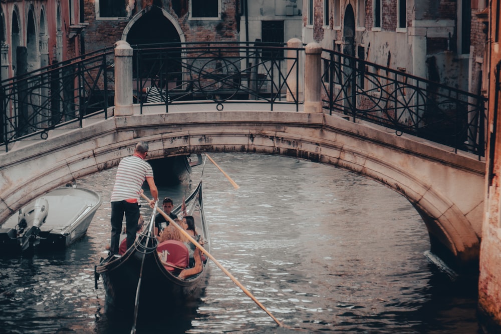 a man riding a gondola down a river under a bridge