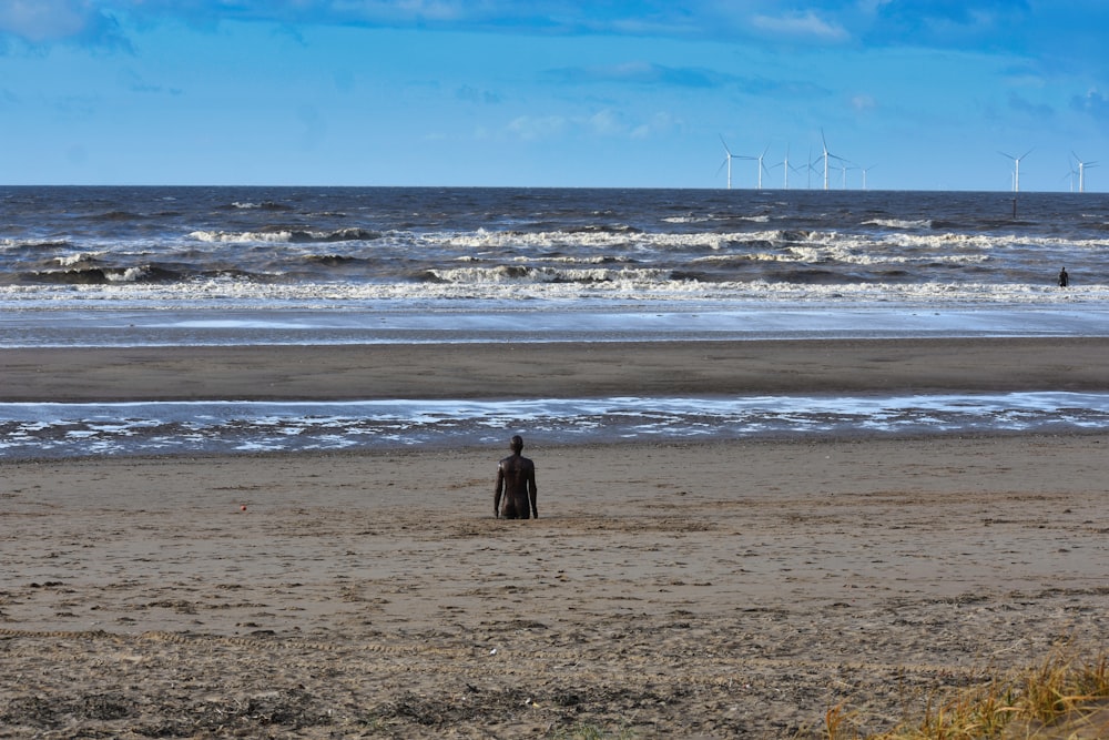 a man standing on top of a sandy beach next to the ocean