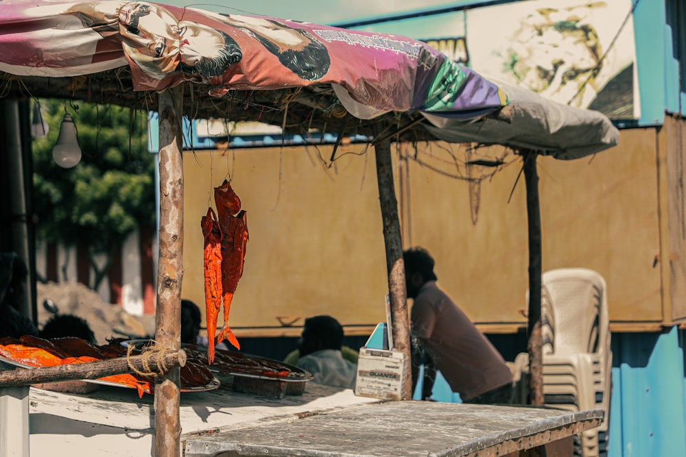 a man sitting under an umbrella next to a table