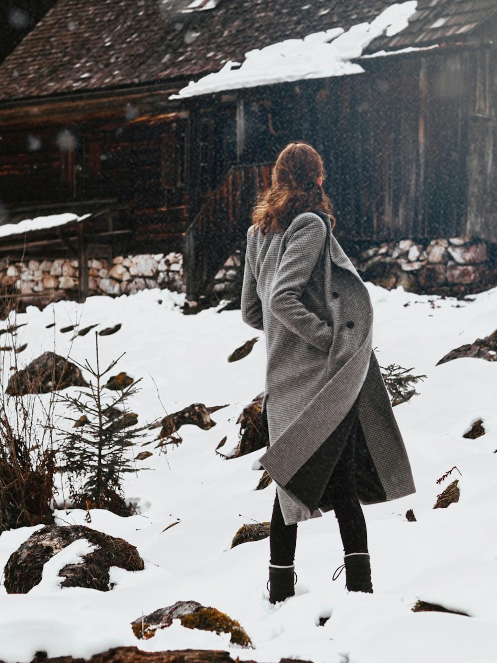 a woman standing in the snow in front of a building