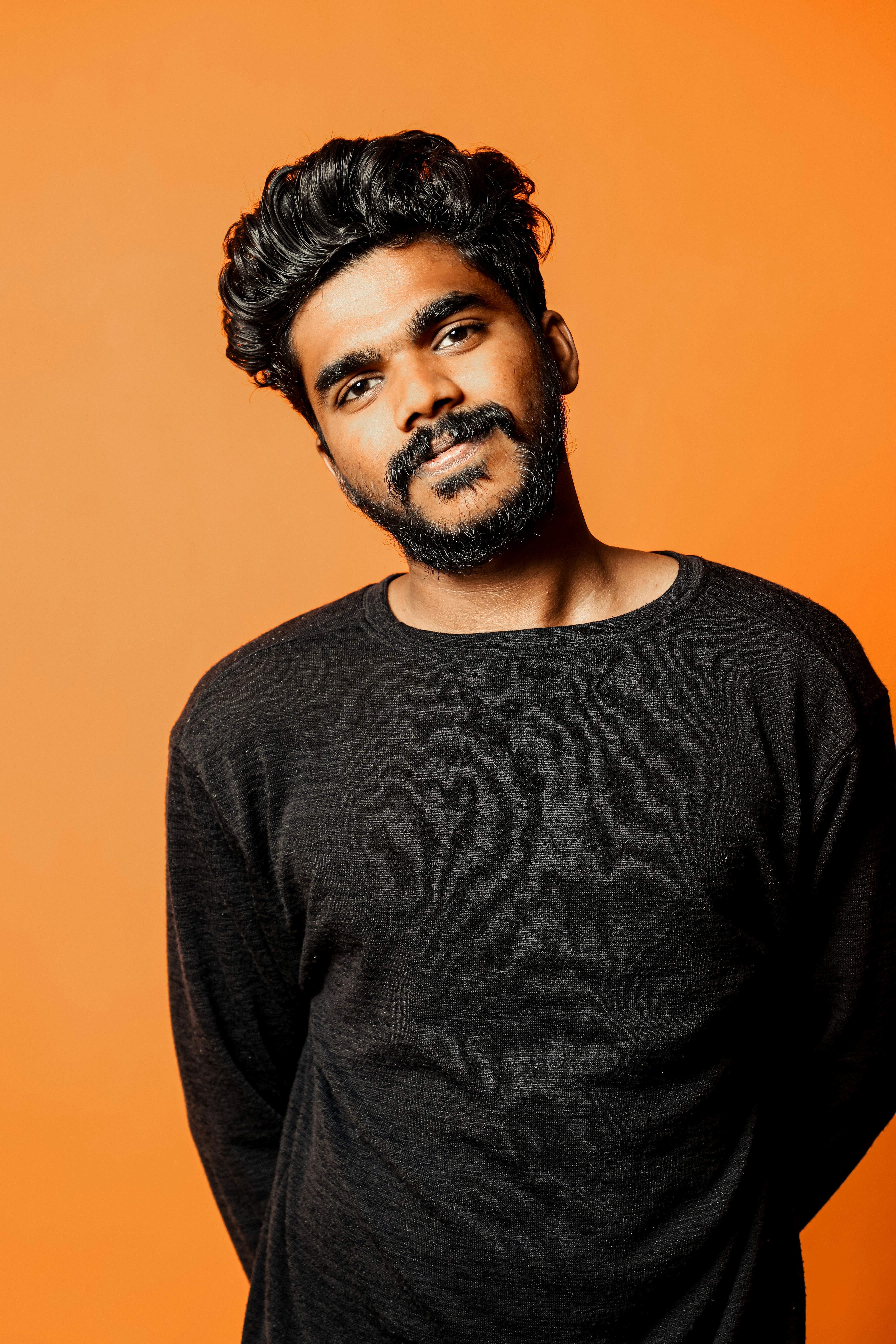 Un hombre parado frente a un fondo naranja