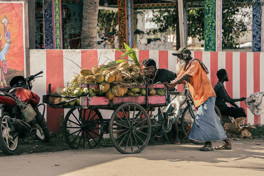 a man pushing a cart full of fruit down a street