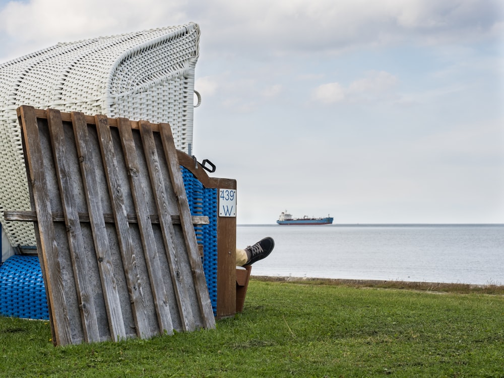 a chair sitting on top of a green field next to a body of water