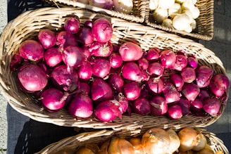 baskets of onions and garlic on display at an outdoor market