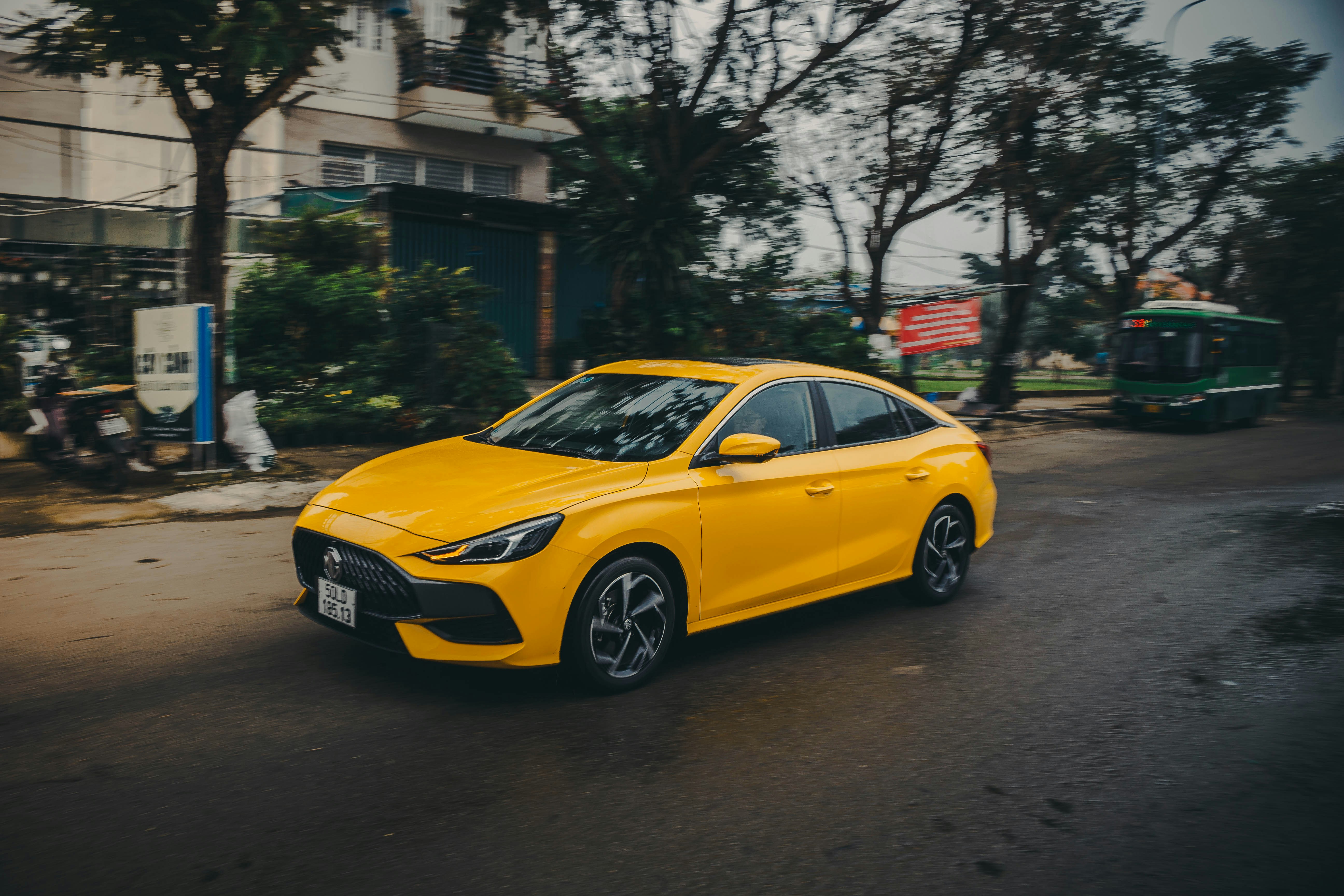 a yellow car is driving down the street