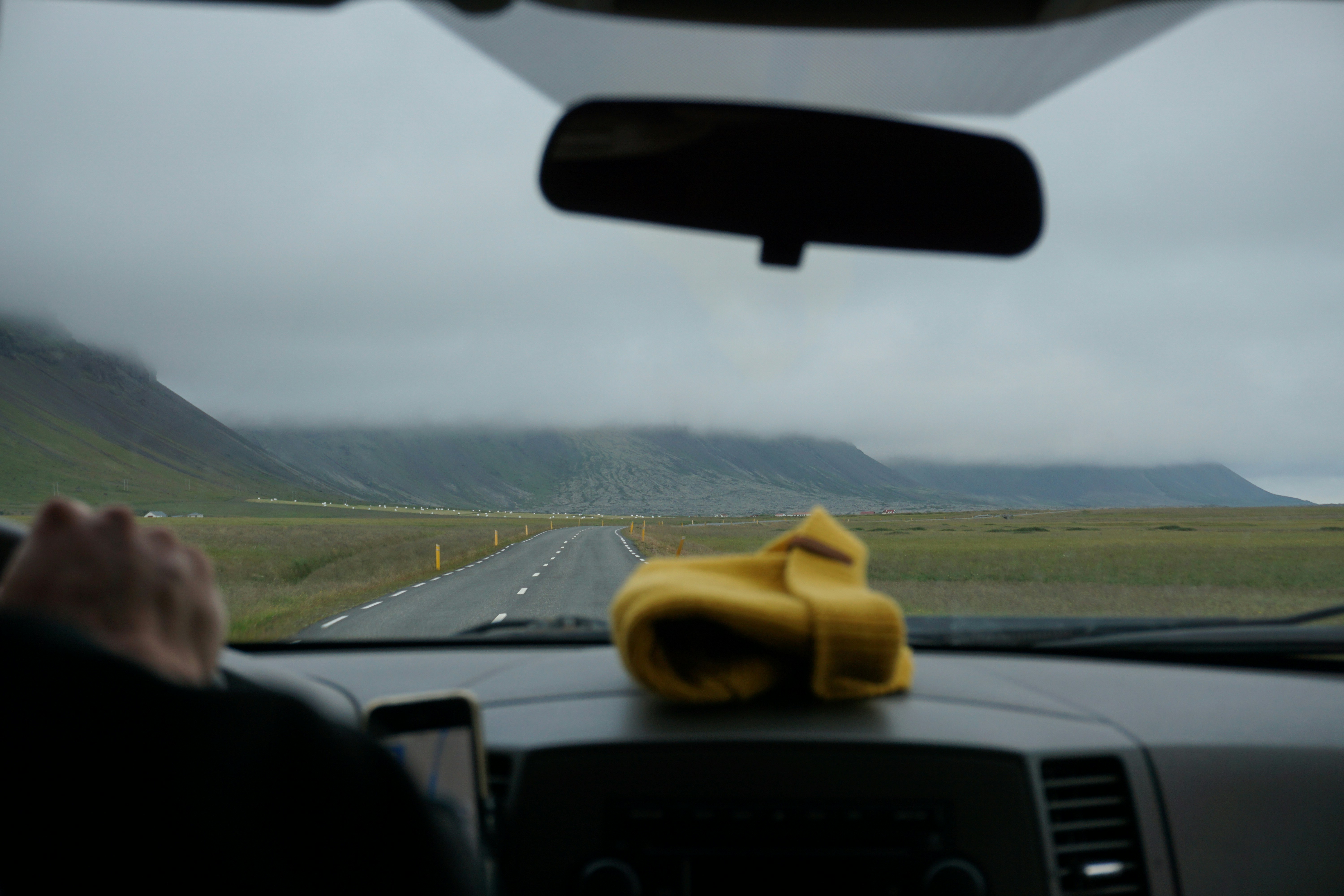a person driving a car on a road with mountains in the background