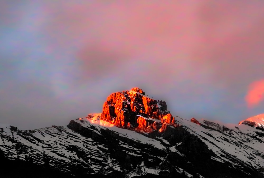 a mountain covered in snow under a cloudy sky