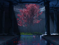 A mystical scene featuring a vibrant red-leaved tree illuminated by beams of light in the center of an ancient, shadowy structure. The tree stands on a grassy patch surrounded by columns with ivy, located under a domed ceiling. A serene pool of water reflects the tree and scattered red petals on its surface.