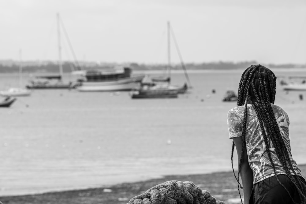 a woman with dreadlocks looking out at boats in the water
